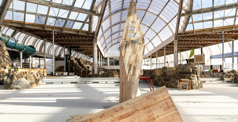 Bouwwerk gemaakt is van kruislaaghout van tweedehands pallets in het oude lege zwembad Tropicana, onder koepelglas dak. 