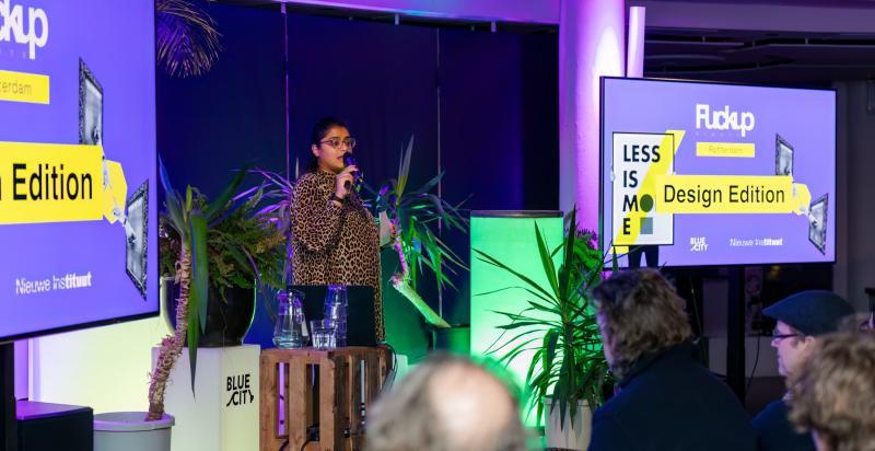 Vrouw spreekt op een podium in BlueCity het aanwezige publiek toe.