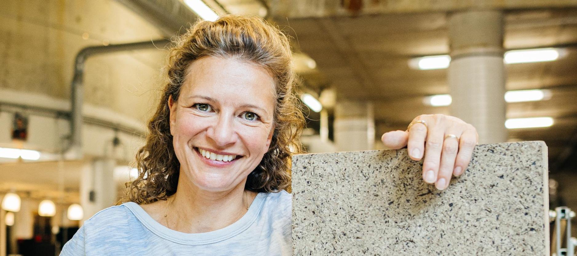 portretfoto van Marjanne Cuypers, staat in de werkplaats met een plaat van zeewier (SeaWood) in haar hand.