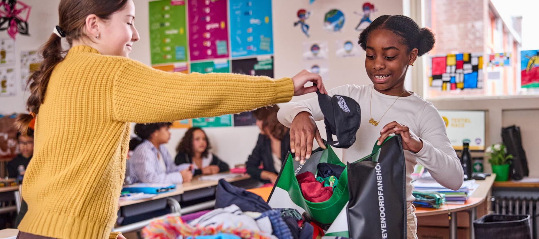 Twee basisschoolleerlingen die textiel in een tas doen.