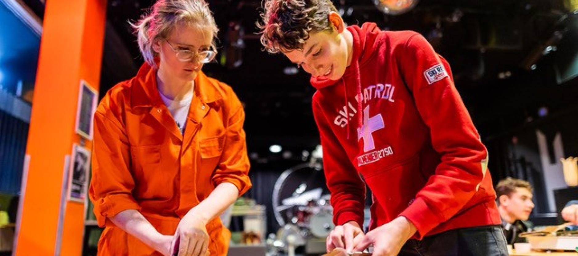 Een vrouw begeleidt een jongen aan een tafel met een creatieve creatie die hij zelf ontworpen heeft.