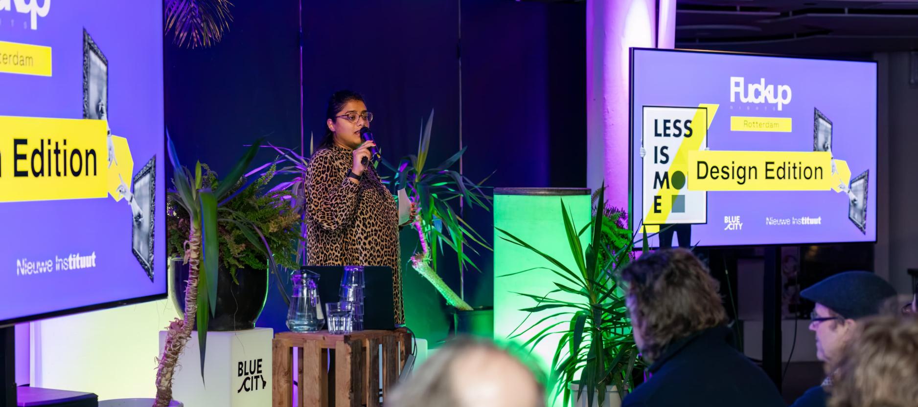 Vrouw spreekt op een podium in BlueCity het aanwezige publiek toe.