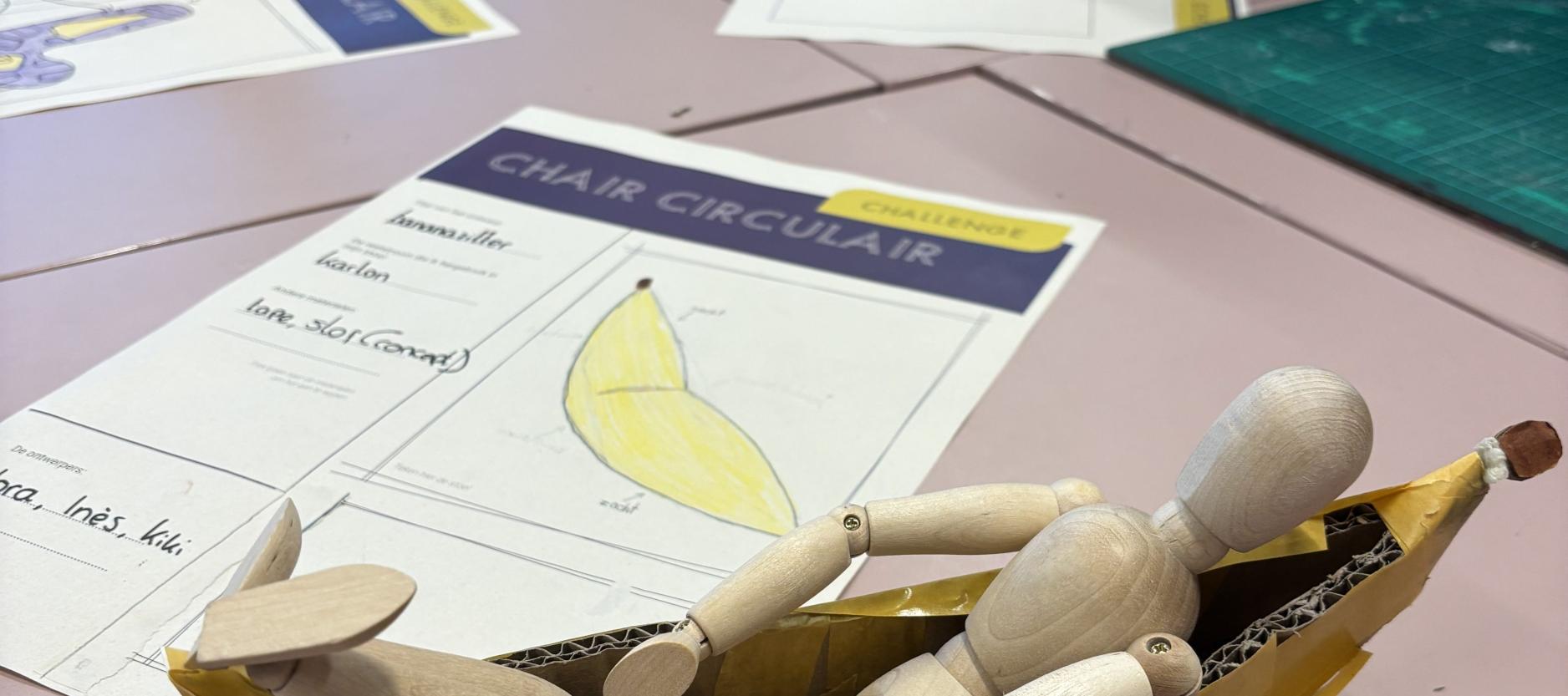 Een houten poppetje ligt in een schaalmodel van een relaxte stoel.