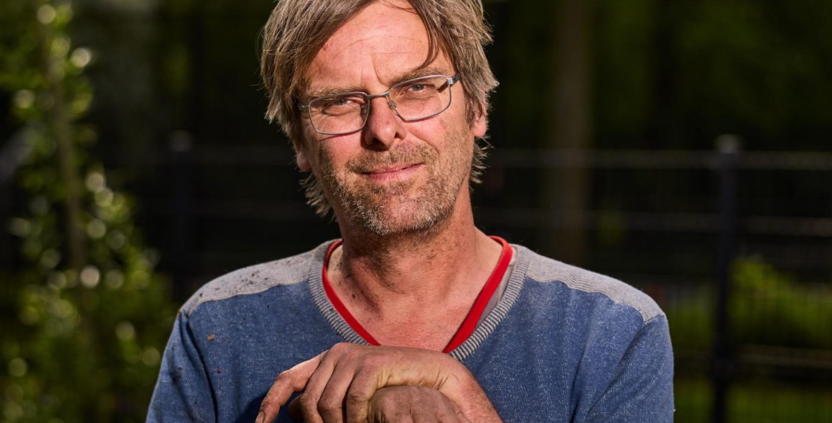portret foto man in de tuin, met handen bevuild door de aarde houdt hij een schep vast.
