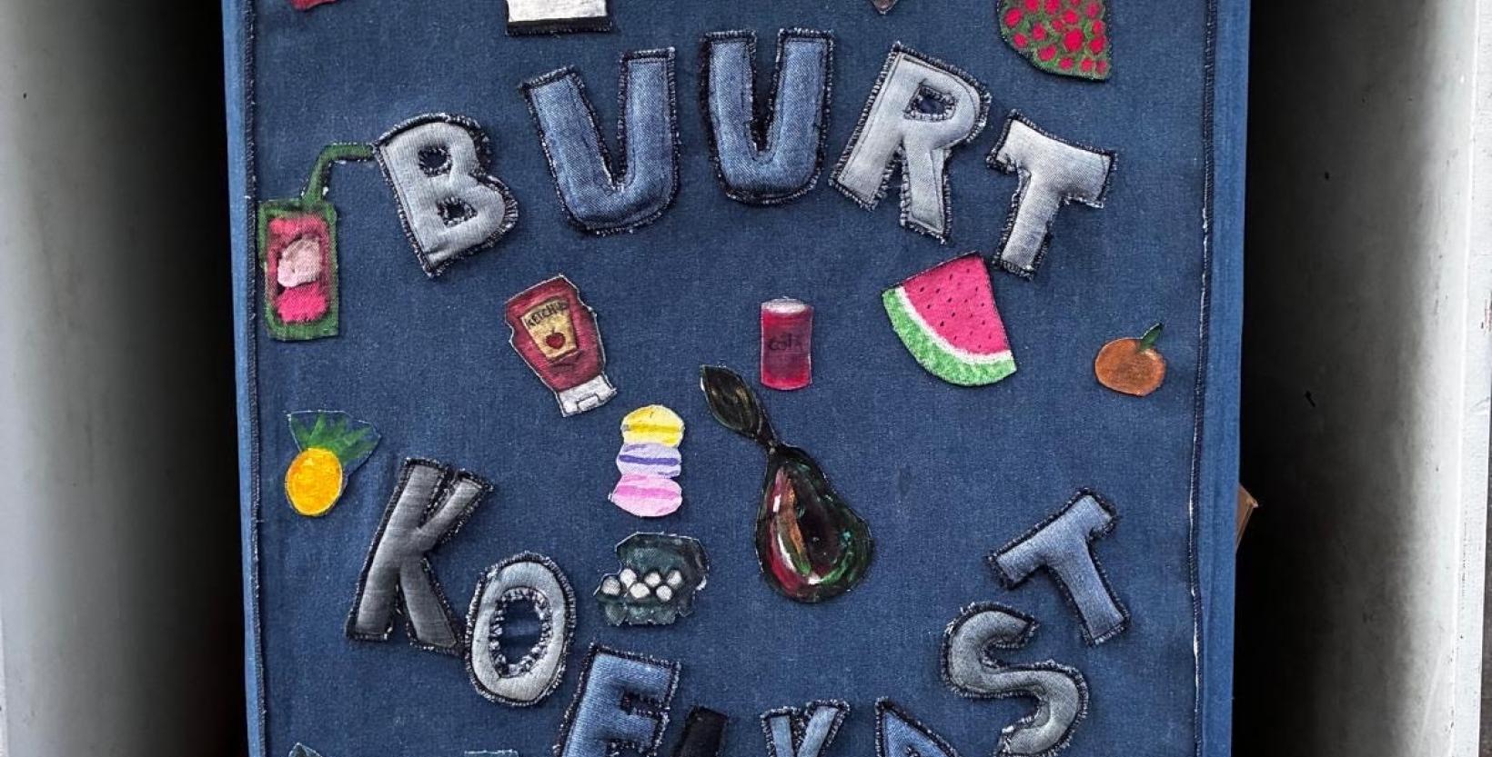 Buurtkoelkast waarvan de deur bekleed is met spijkerstof en emblemen.