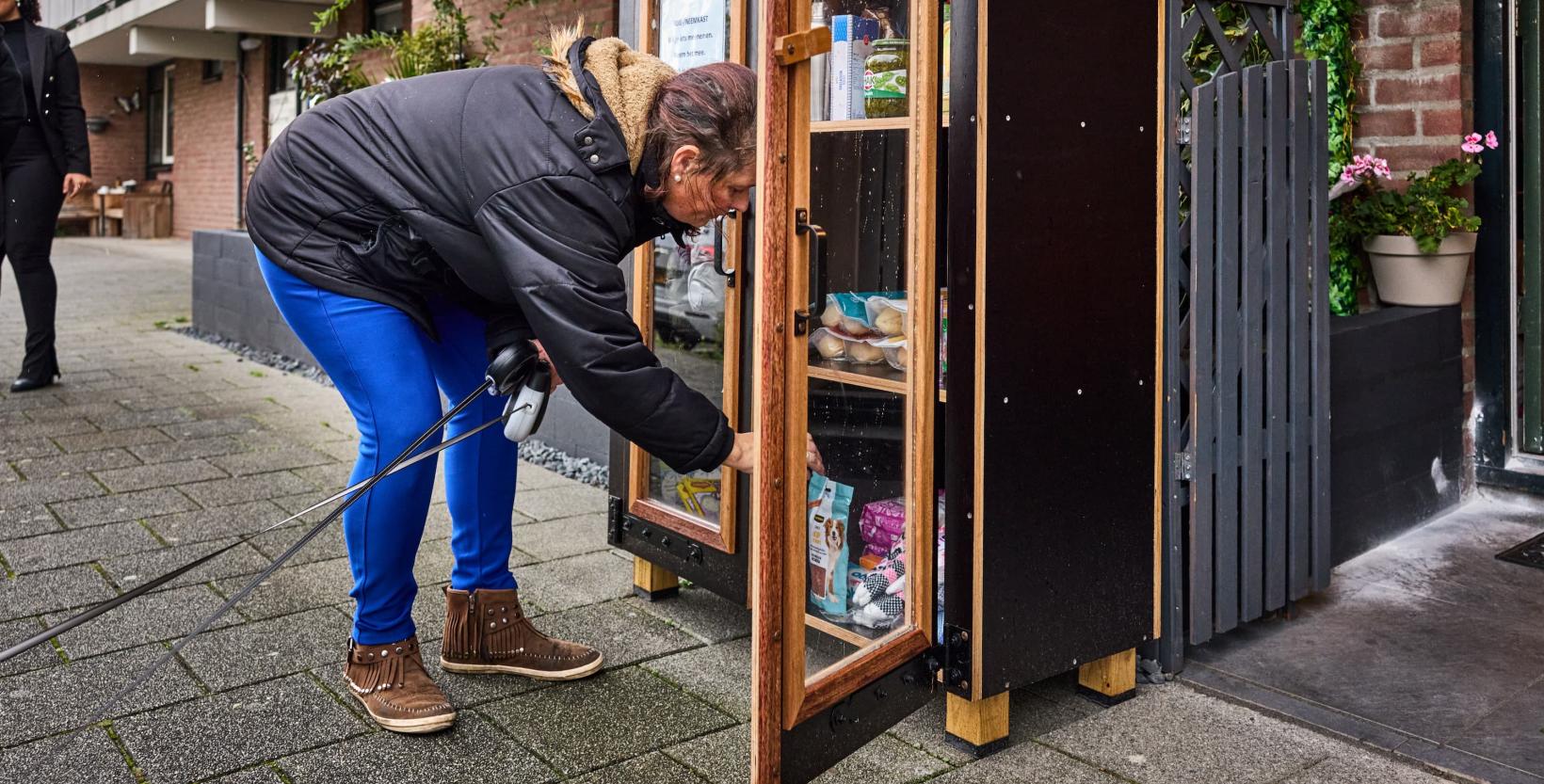 Vrouw zet een product in een Rotterdamse weggeefkast.