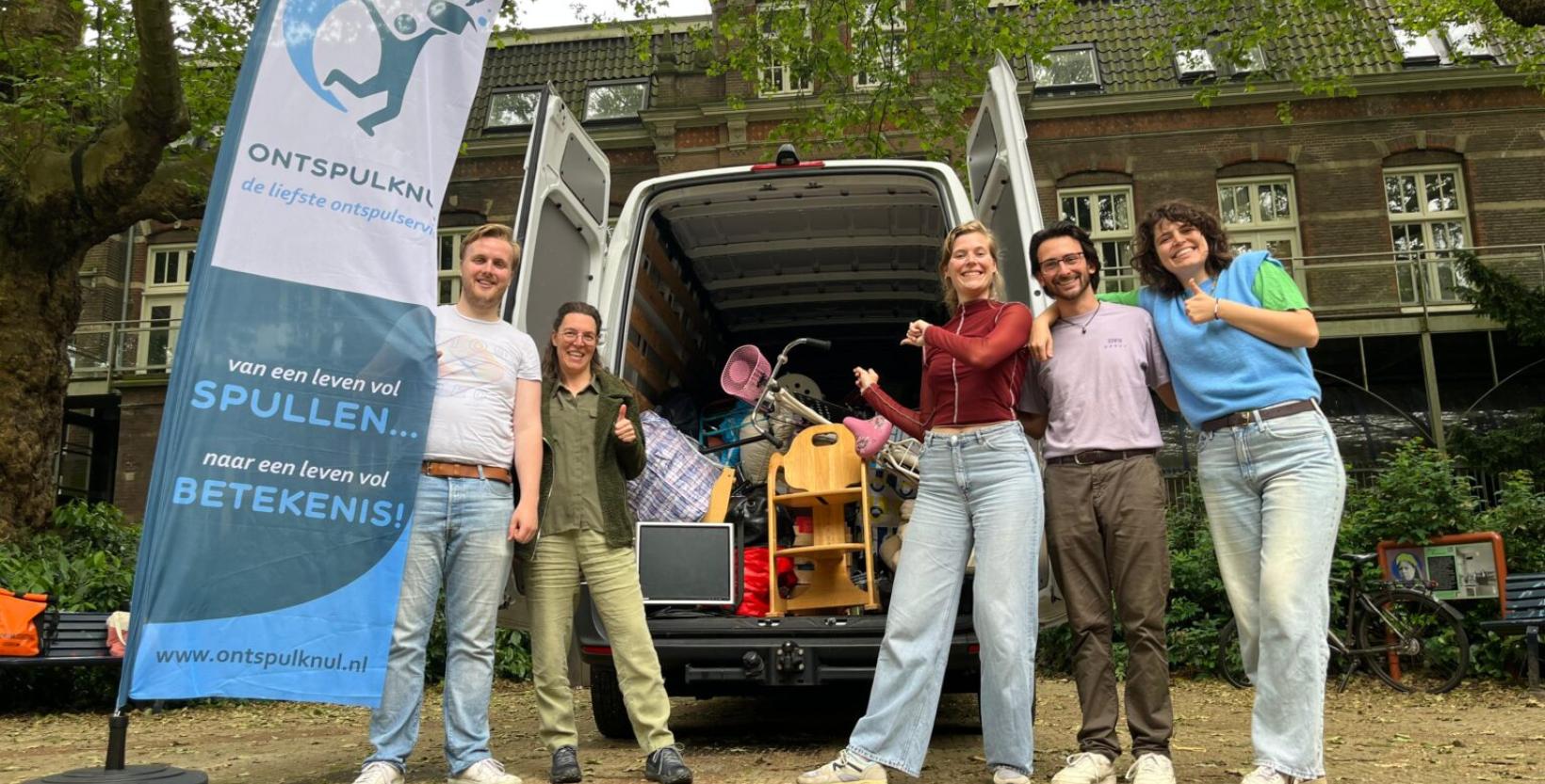 Vijf mensen van Stichting de Ontspulknul op een rij met bruikbare spullen die ze hebben opgehaald.