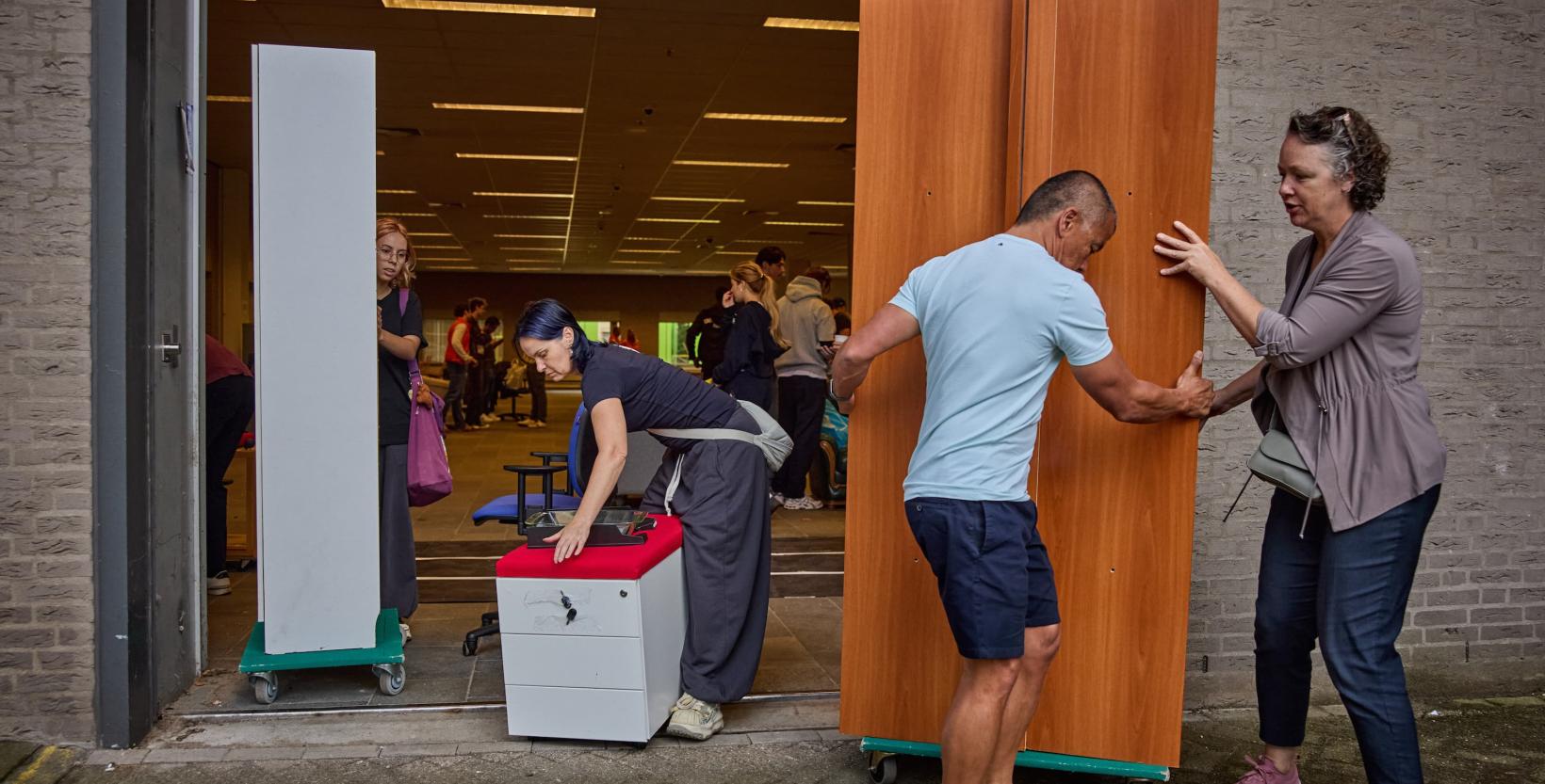 Studenten lopen rond tussen tweedehands meubels die zijn uitgestald in een grote hal.